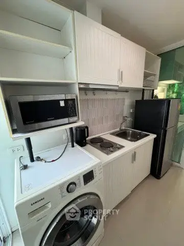 Compact kitchen with modern appliances including fridge, microwave, and washing machine in a sleek design.