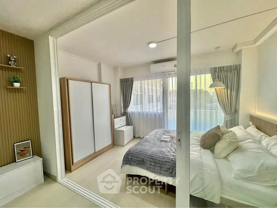 Modern bedroom with sliding glass doors, cozy bed, and ample natural light.