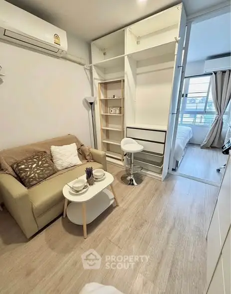 Cozy living room with modern furniture and open closet, adjacent to a bright bedroom.