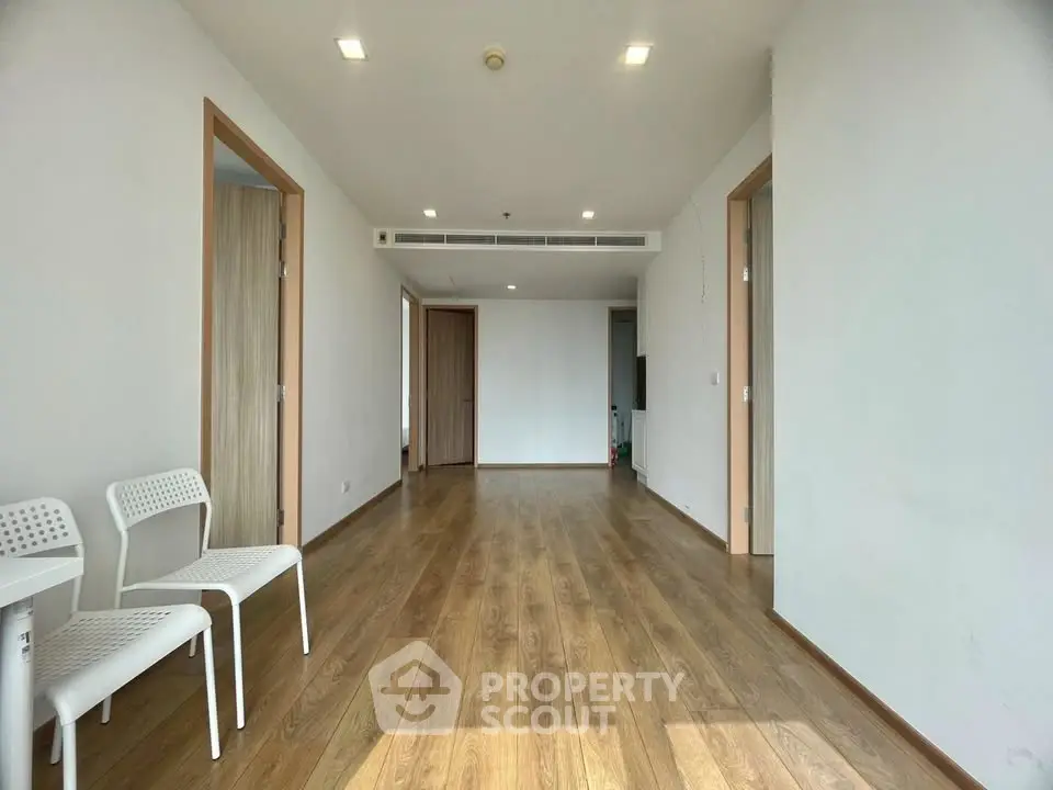 Spacious empty room with wooden flooring and modern lighting, ideal for customization.