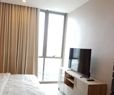 Modern bedroom with large window and TV stand, featuring elegant curtains and natural light.