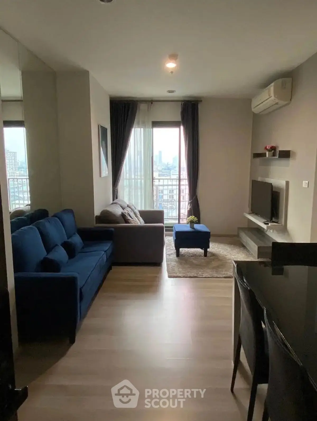 Modern living room with city view, featuring stylish furniture and natural light.