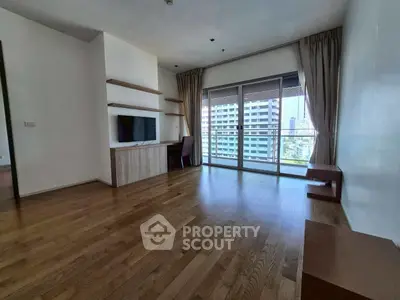 Spacious living room with wooden flooring and large windows offering city views.