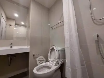 Modern bathroom with sleek fixtures and neutral tiles, featuring a toilet and shower area.