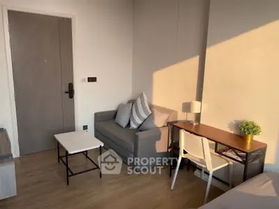 Cozy living room with modern sofa, desk, and warm sunlight ambiance.