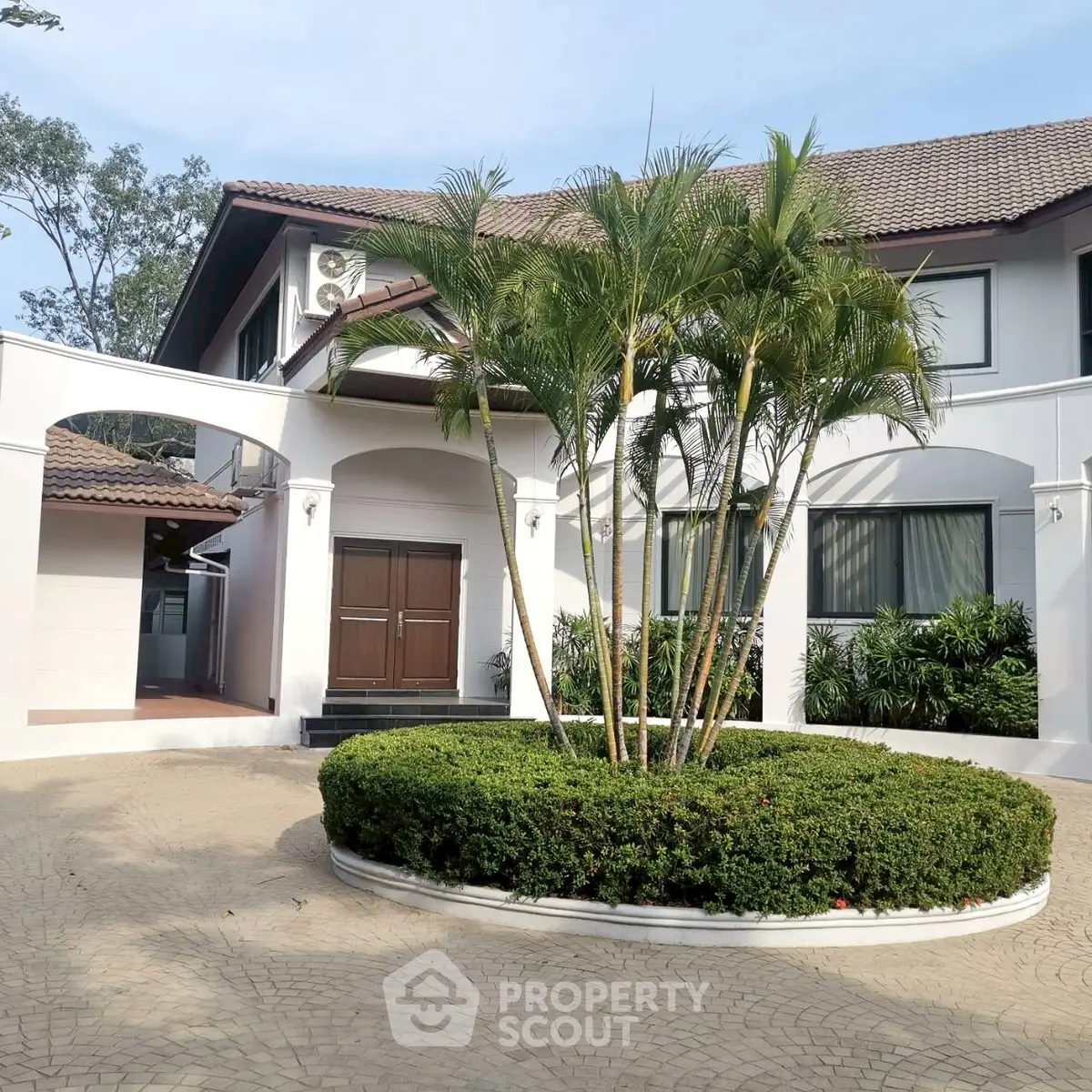 Elegant two-story house with lush landscaping and circular driveway