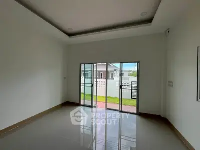 Spacious empty room with large sliding glass doors leading to a garden view.