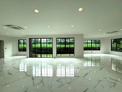 Spacious modern living room with large windows and marble flooring, offering serene garden views.