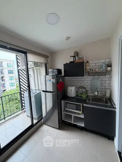 Modern compact kitchen with balcony view, featuring sleek appliances and stylish cabinetry.