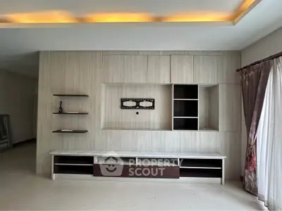 Spacious living room with modern built-in entertainment unit and elegant ceiling lighting.