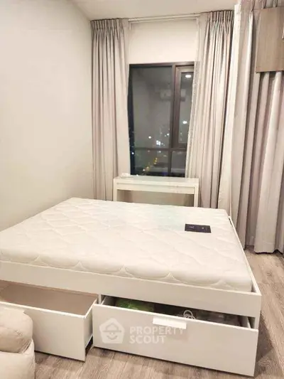 Modern bedroom with sleek white bed frame and city view window.