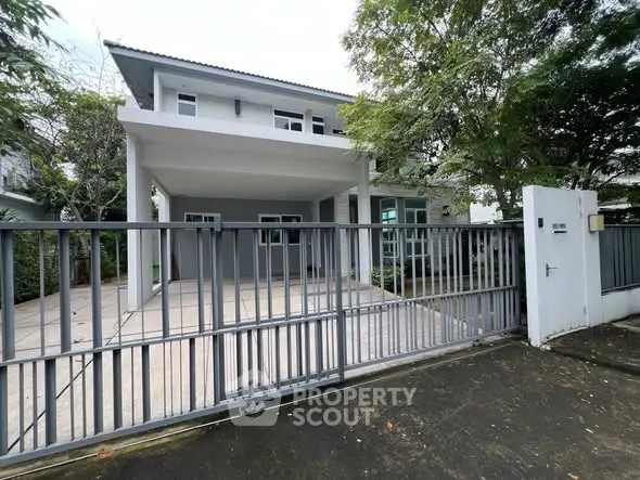 Modern two-story house with spacious driveway and gated entrance.