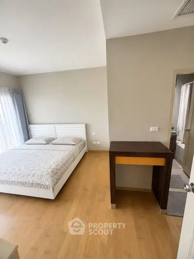 Spacious bedroom with modern decor and natural light in a stylish apartment.
