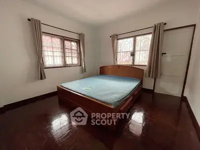 Spacious bedroom with wooden flooring and large windows in a cozy home.