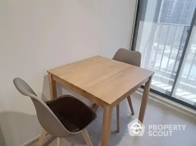 Modern dining area with wooden table and chairs near balcony window