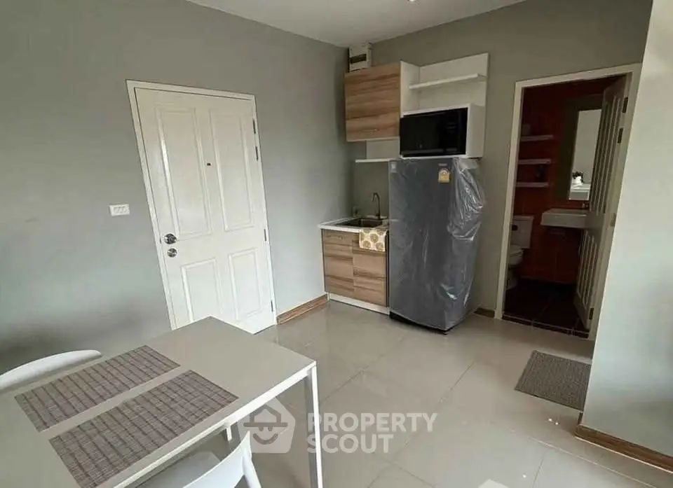 Modern compact kitchen with fridge and microwave in cozy apartment