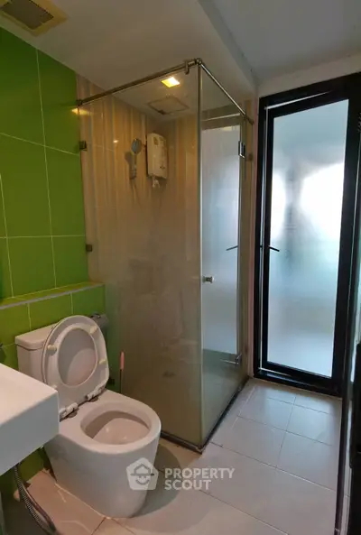 Modern bathroom with glass shower and green accent wall