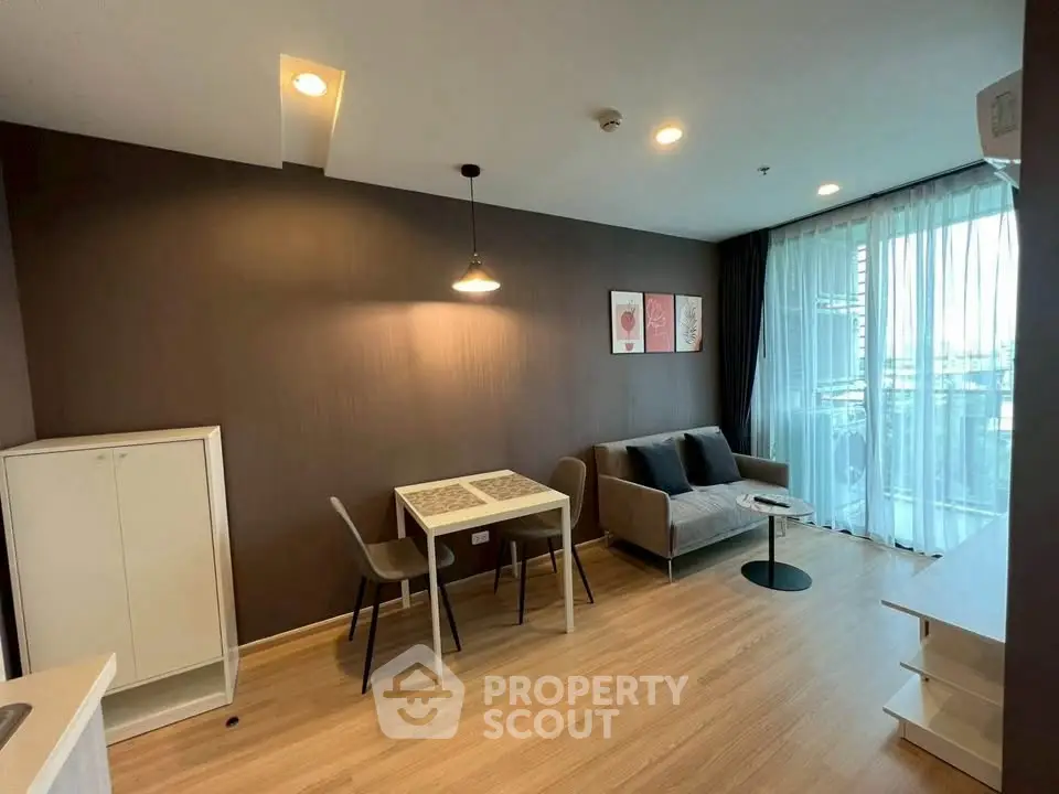Modern living room with cozy sofa and dining area, featuring large windows and stylish decor.