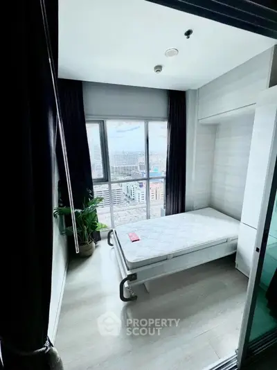 Modern bedroom with city view, featuring large window and minimalist decor.