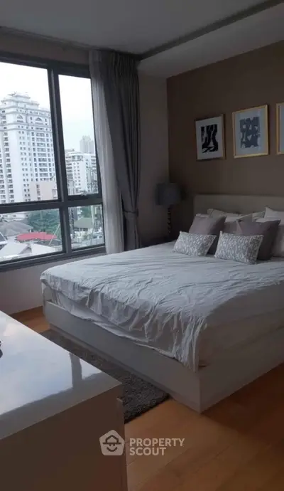 Modern bedroom with large window offering city view, featuring stylish decor and cozy ambiance.
