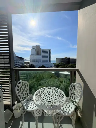 Charming balcony with elegant furniture and stunning city view under a bright blue sky.