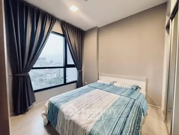 Cozy bedroom with large window and city view, featuring modern decor and stylish curtains.