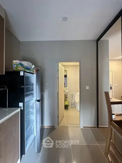 Modern kitchen with sleek design and open layout leading to a bathroom, featuring contemporary appliances.