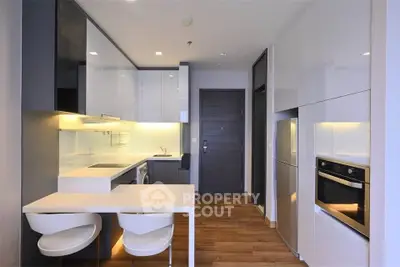 Modern kitchen with sleek cabinetry, built-in oven, and stylish dining area in a contemporary apartment.