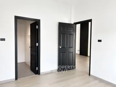Modern interior with sleek black doors and light wood flooring, showcasing minimalist design.