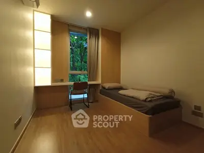 Cozy minimalist bedroom with wooden flooring and a serene garden view.