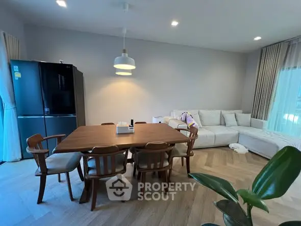 Spacious living room with modern dining set and cozy sofa, perfect for family gatherings.