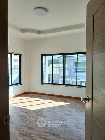 Bright and airy bedroom with large windows and modern flooring, offering a serene view of the neighborhood.