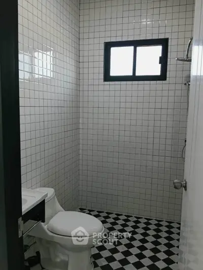 Modern bathroom with checkered floor tiles and sleek white fixtures.