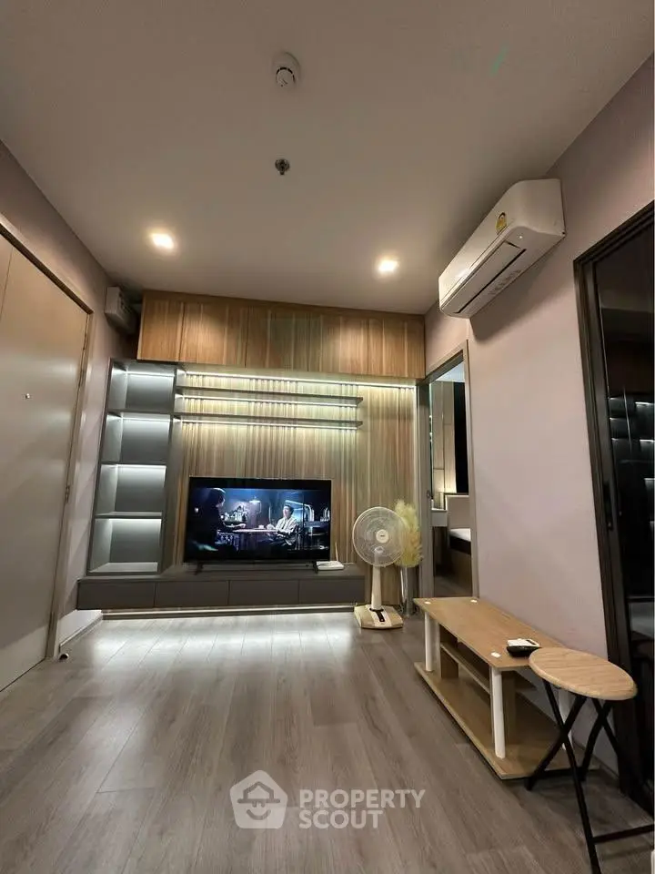 Modern living room with sleek design, featuring a TV, air conditioning, and stylish lighting.