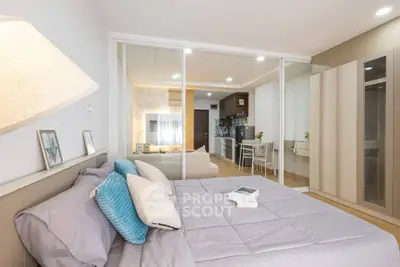 Modern bedroom with open layout to living area and kitchen, featuring stylish decor and ample natural light.