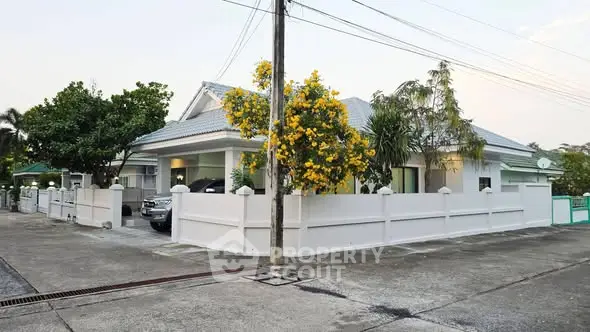 Charming suburban house with lush garden and white fence, perfect for family living.