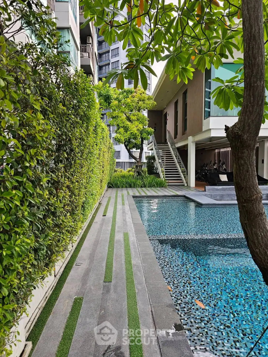 Luxurious modern apartment complex with a stunning outdoor pool and lush greenery.