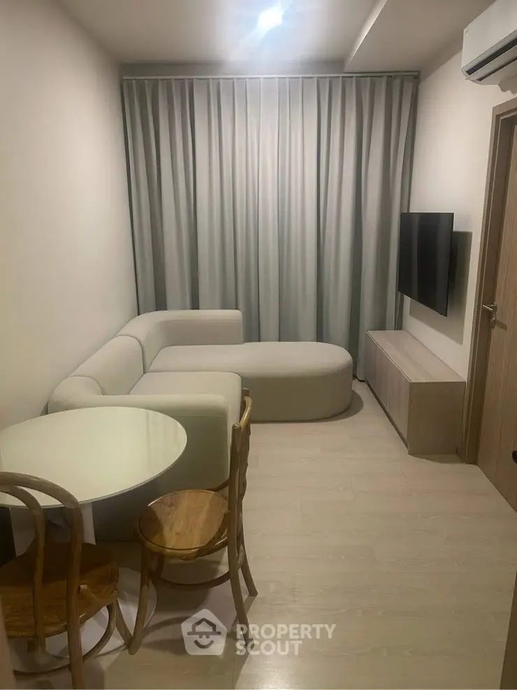 Modern living room with sleek furniture and minimalist design, featuring a cozy sofa and wall-mounted TV.