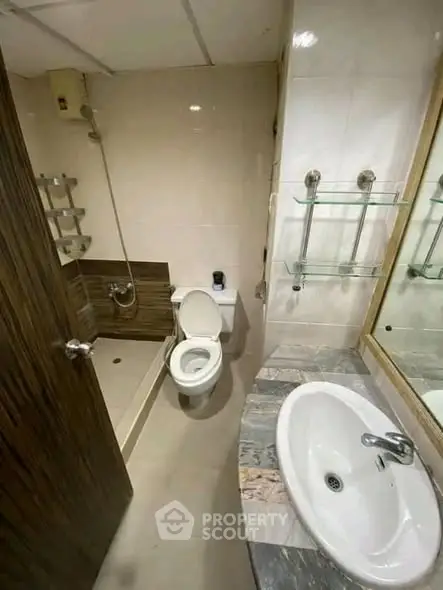 Compact bathroom with modern fixtures and neutral tiles, featuring a shower and sleek sink design.