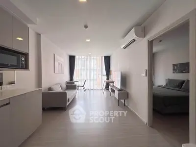 Modern open-plan living room with sleek kitchen and cozy bedroom in a stylish apartment.