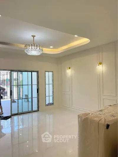 Elegant living room with chandelier and large windows, showcasing modern interior design.