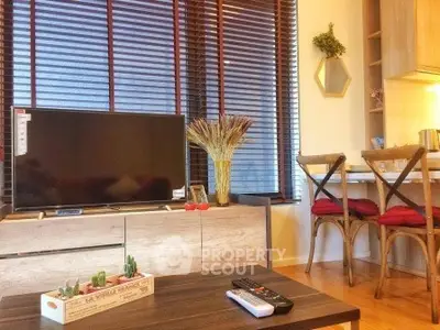 Cozy living room with modern decor and natural light, featuring a TV and dining area.