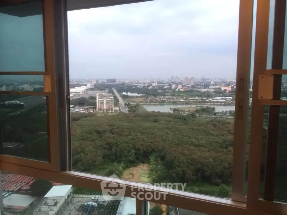Stunning high-rise view from a window overlooking lush greenery and cityscape.