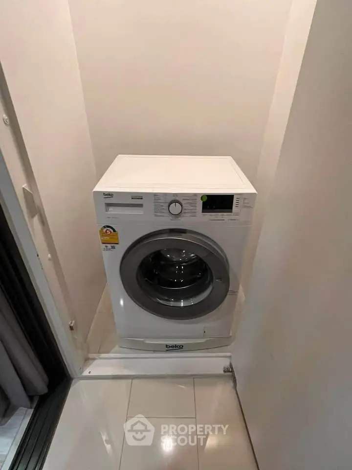 Compact laundry area with modern washing machine in sleek white interior.
