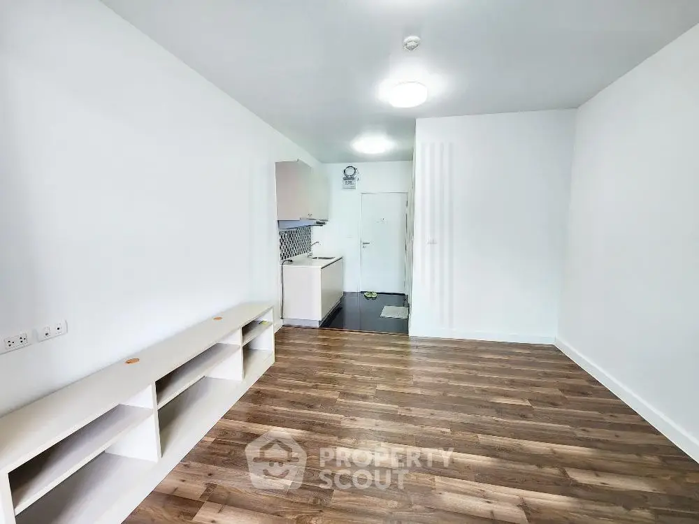 Spacious modern living room with sleek wooden flooring and open kitchen layout.