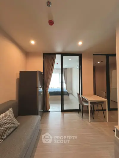 Modern apartment interior with open living and dining area leading to a cozy bedroom.