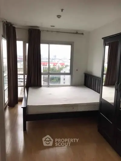 Spacious bedroom with large windows and wooden flooring, offering a bright and airy ambiance.