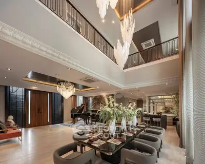 Luxurious open-plan living room with elegant dining area and grand piano, featuring high ceilings and chandeliers.