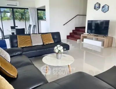 Spacious modern living room with sleek black leather sofas and large TV, perfect for entertaining.