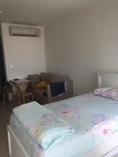 Cozy bedroom with air conditioning and a small seating area, perfect for relaxation.